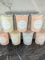 A variety of naturally colored Colorwayz cotton candy tubs in flavors like Bunny Floss, Watermelon, Strawberry, Bubble Gum, Caramel, and Blueberry, neatly displayed against a marble background.