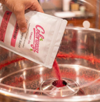 Pouring Colorwayz strawberry cotton candy sugar into a cotton candy machine